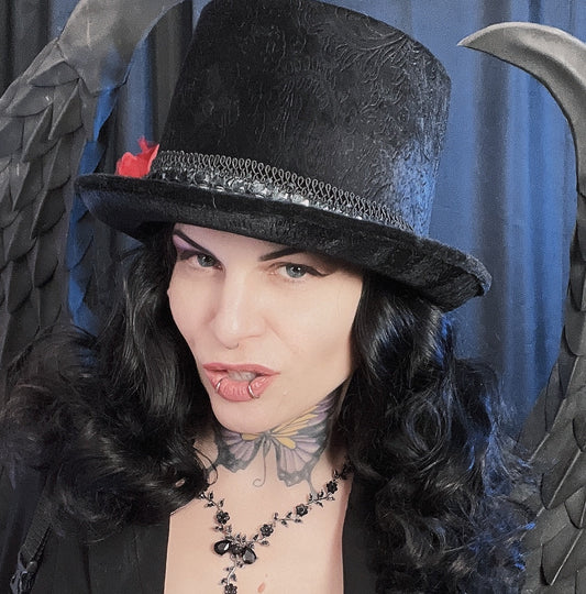 Woman with black curly hair wearing a black top hat and gothic necklace offering private 45-minute tarot reading session via Google Meet